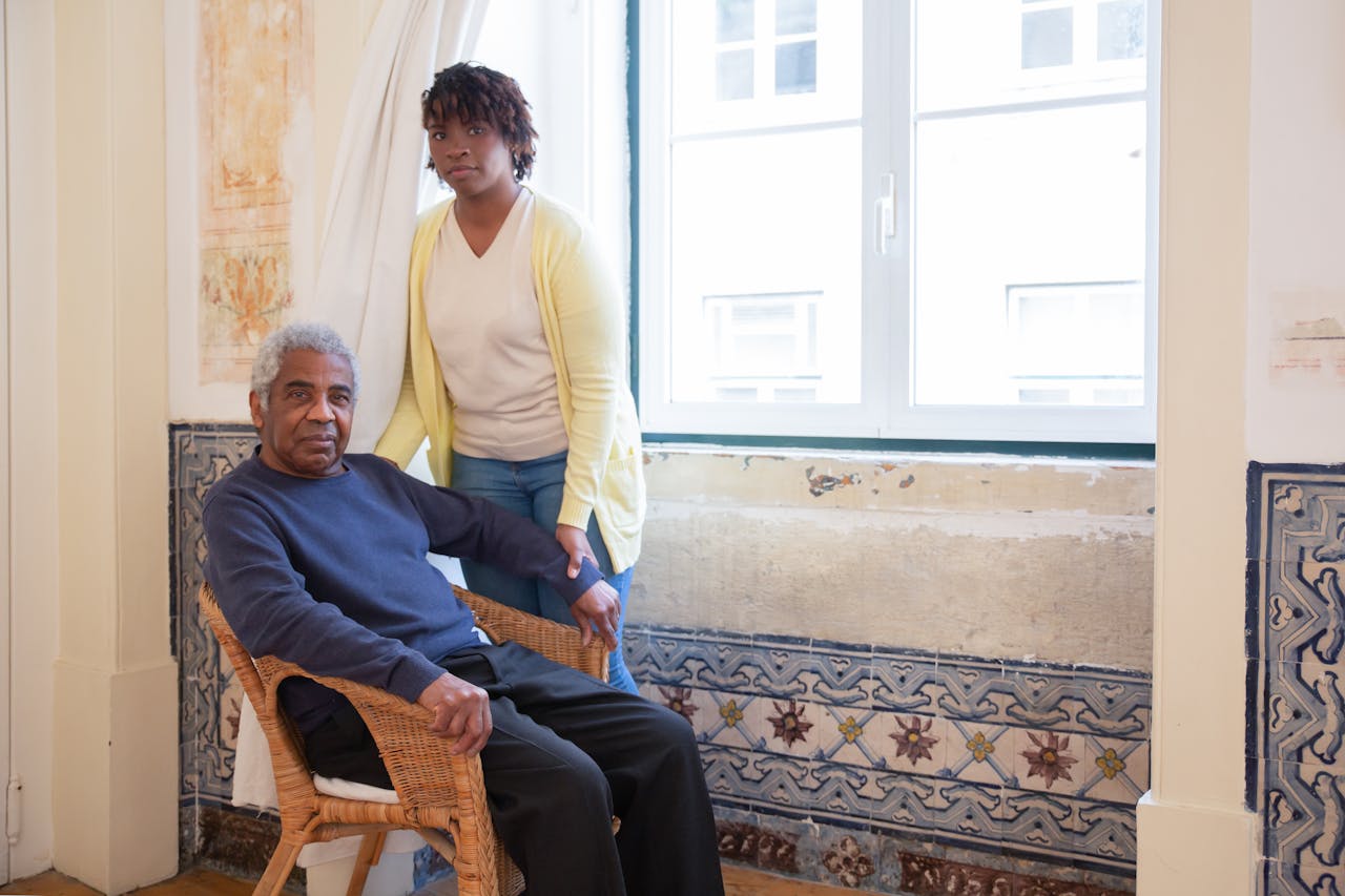 Mastering the First Impression: Your intriguing post title goes here Elderly man seated with caregiver standing beside him at home in Portugal.
